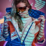 Close up portrait of a young tattooed racer woman posing in a vivid neon studio over text projection