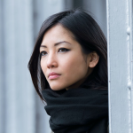 Pretty asian young woman looking sideways in the street.