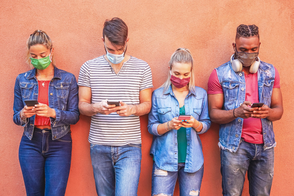 People using apps too much, Picture of young people on a walls looking at their smartphone apps.